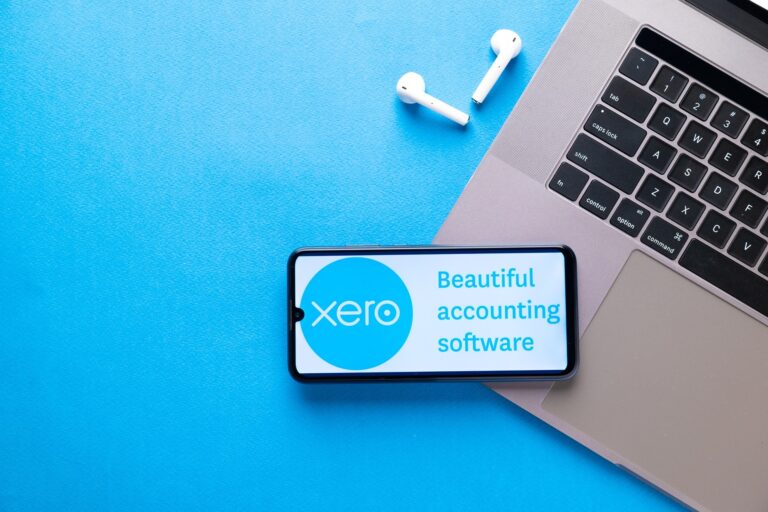 Xero displayed on a smartphone near modern laptop on blue background