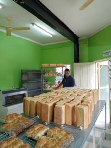 Baker with fresh bread loaves, Ibubu Bakery Solomon Islands