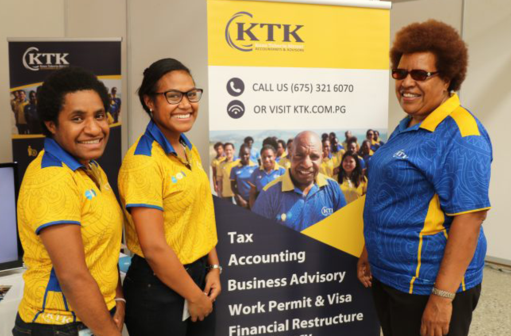 women promoting an event in a stand with a banner