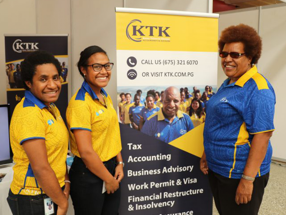 women promoting an event in a stand with a banner