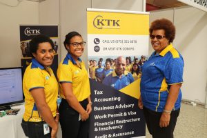 women promoting an event in a stand with a banner