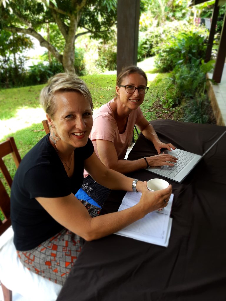 Two women working on admin in a garden