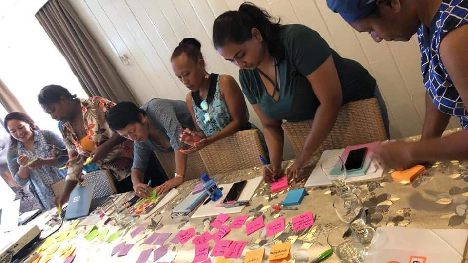 women are working together on a big table at The Fusion Hub in Fiji