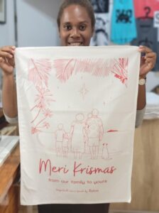 Pandanus Vanuatu employee holding Meri Krismas tea towel